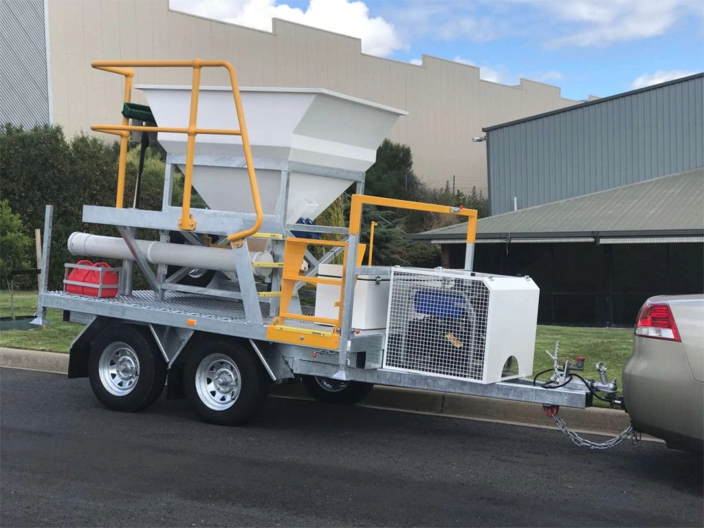 White Sandbagging Trailer with Safety Yellow Rails & Steps on road in front of green grass and buildings