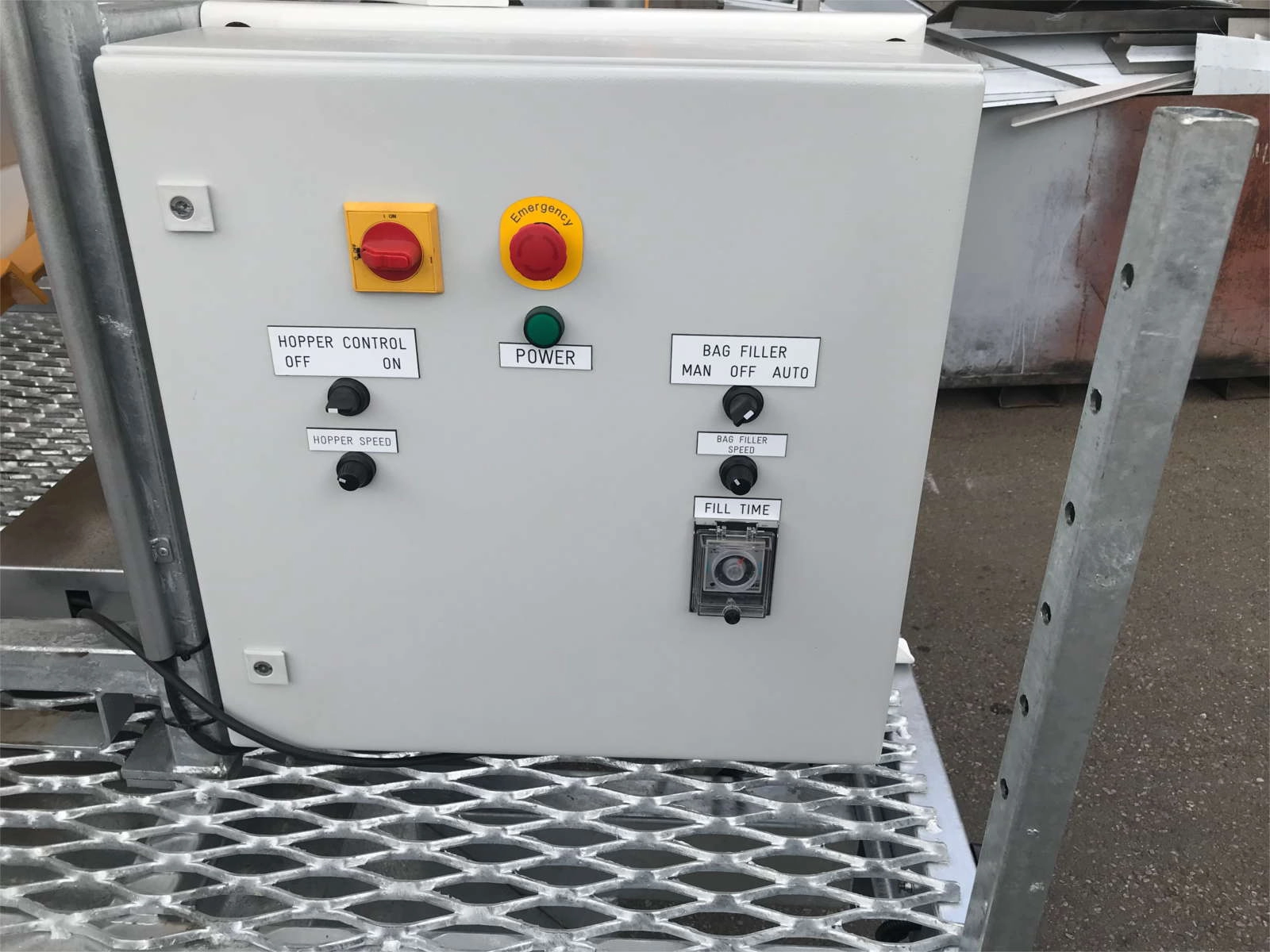 Can customise any function, aesthetic, or feature. Photo of Control board with hopper control, hopper speed, bag filler control, & bag filler speed dials, fill time gauge, and big red emergency stop button with yellow emergency signage.